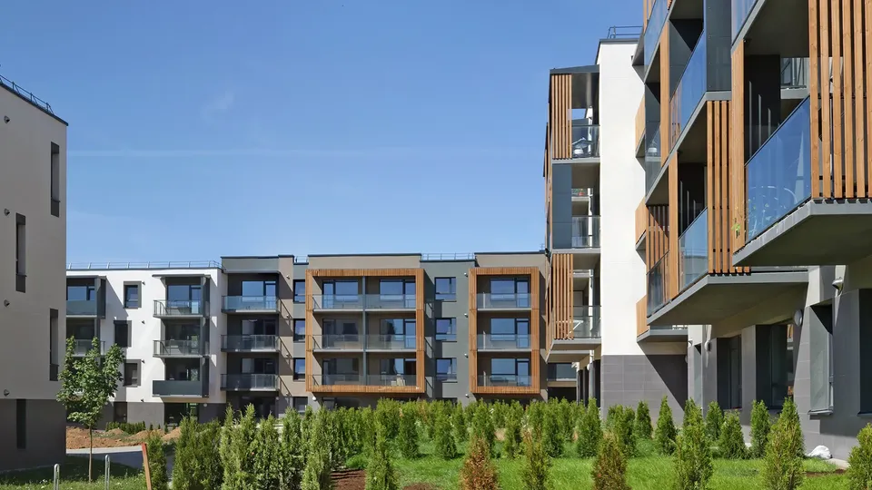 Moderne boligbygninger med træ- og hvide facader omringet af grøn gårdsplads.