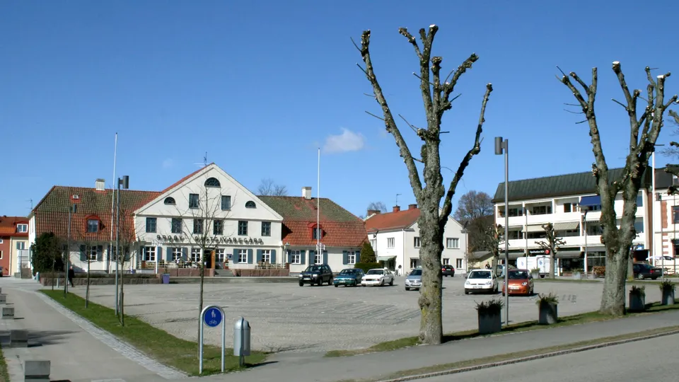 Parkeringsplats omgiven av vita byggnader och nakna träd i Skåne.