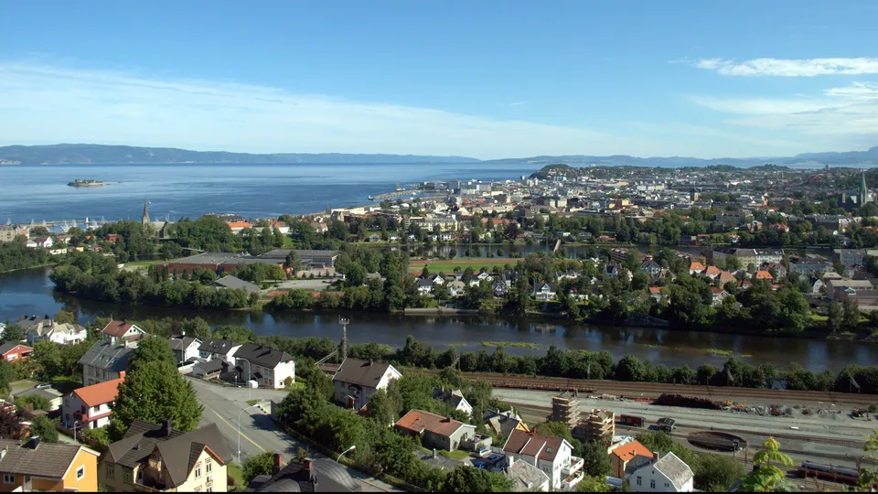 Luftfoto av en skandinavisk by med elv, boligområder og fjern bukt.