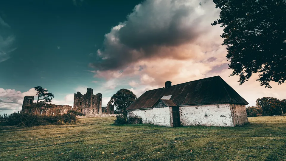 Solar panel installations. County Meath: Abandoned white cottage under cloudy sky.
