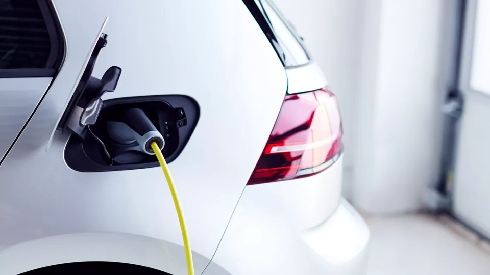 White electric vehicle charging with yellow cable connected to charging port.