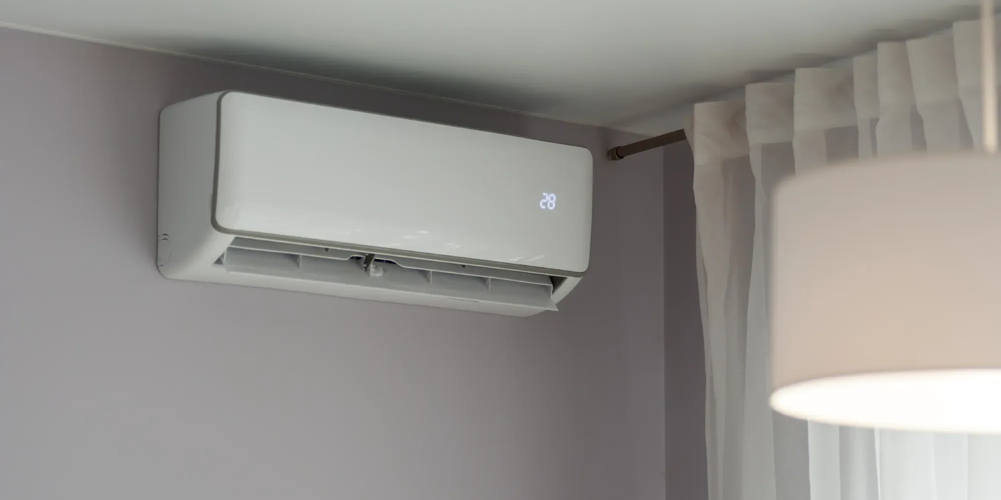 White wall-mounted air conditioning unit displaying 28 degrees on digital display.