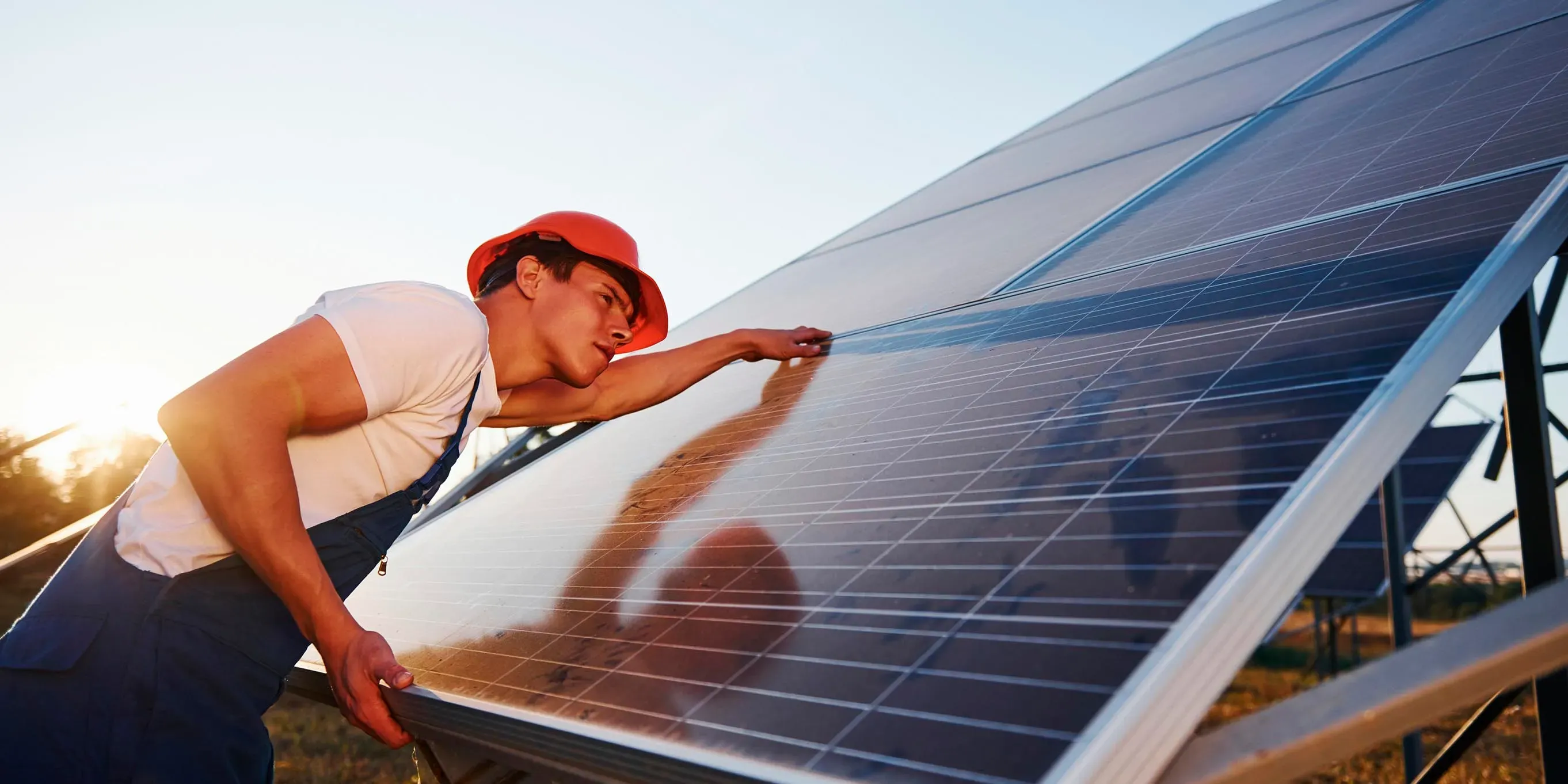 Trabajador limpiando panel solar con spray de agua.