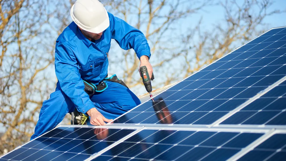 Técnico de paneles solares utilizando equipo de prueba en instalación en azotea.
