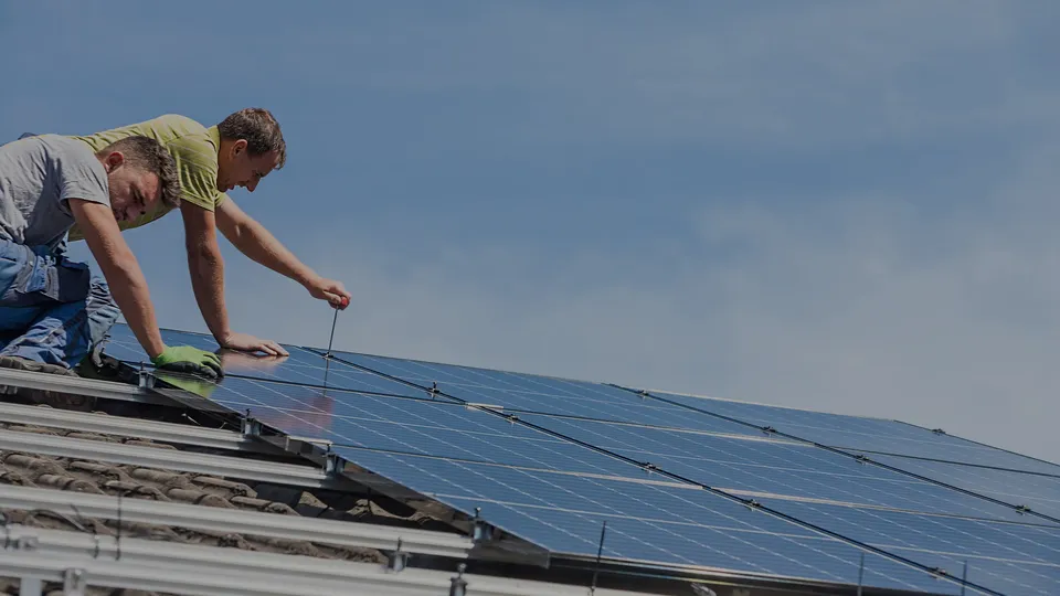 Dos trabajadores instalando paneles solares en un techo.