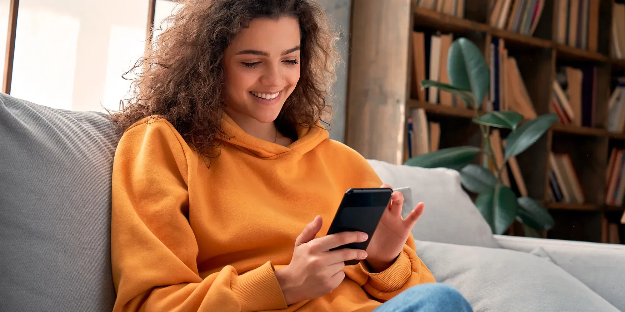 Mujer sonriendo mientras mira su teléfono inteligente.