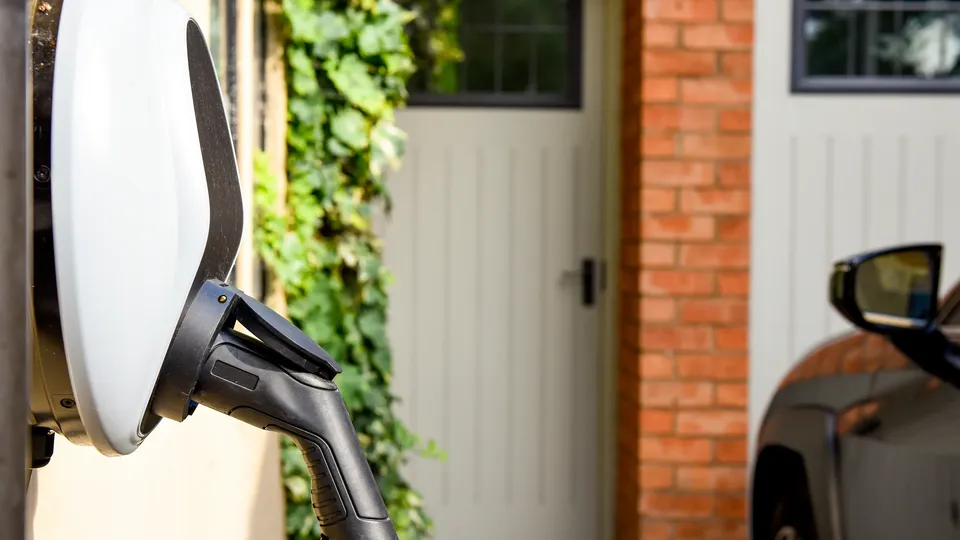 Pictured is an EV charger in use outside a red brick house.