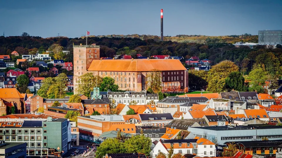 Luftfoto af Kolding by med slot og farvede tage.