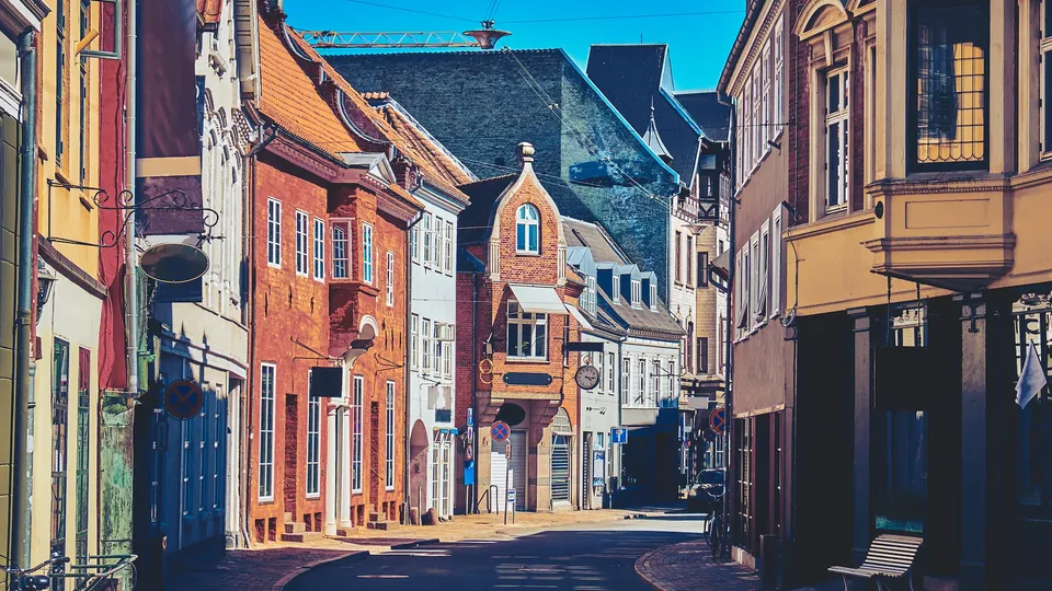 Farverig historisk gade med murstena bygninger og klar himmel.