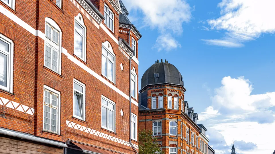 Bilede af Esbjerg: Victorianske murstensbygninger med kuppeltårn under blå himmel.