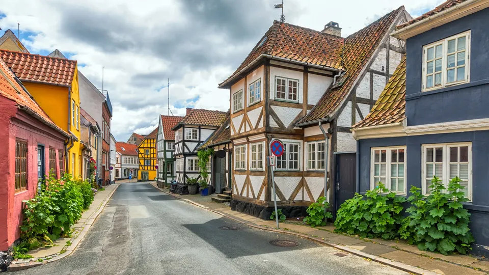 Billede af Fyn: Farverige bindingsværkshuse langs en stille brostensgade.