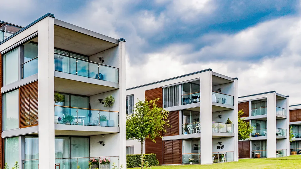 Billede af Horsens: Moderne boligbygninger med glas altaner, der har udsigt til en græsplæne.