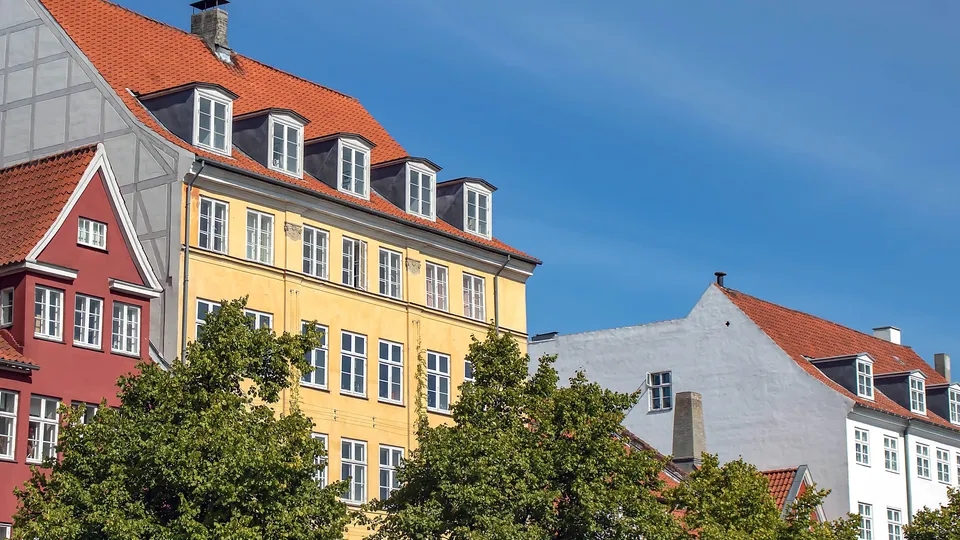 Billede af Sjælland: Farvefulde historiske bygninger med røde tegltage og kvistvinduer under blå himmel.
