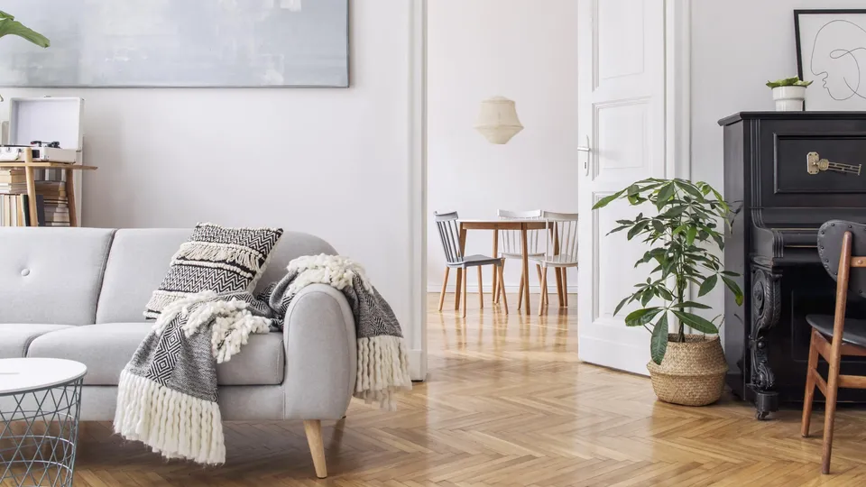 Modernt skandinaviskt vardagsrum med grå soffa och svart piano.