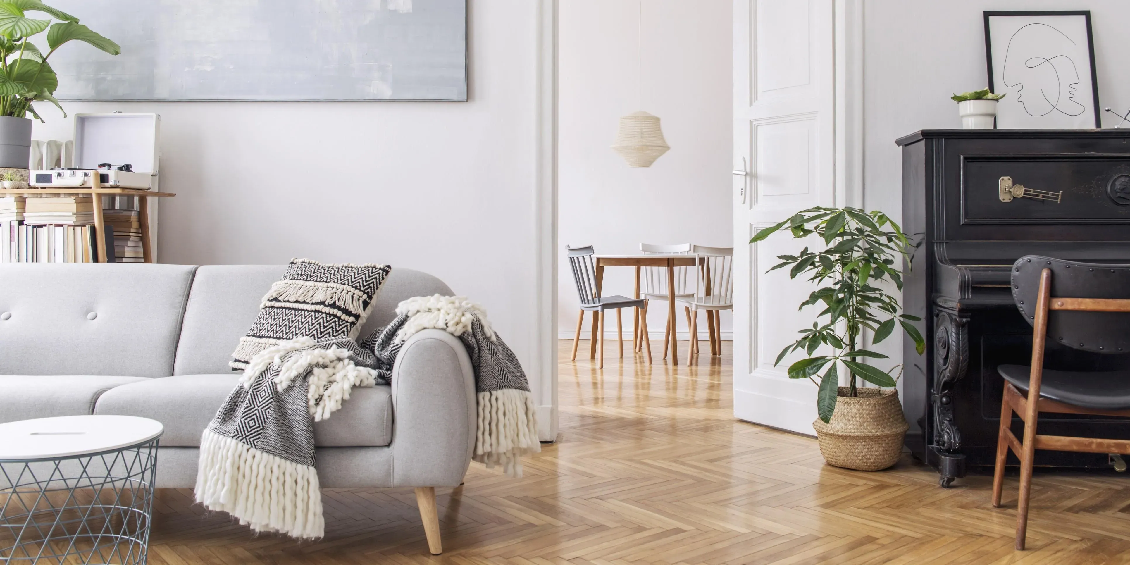 Modernt skandinaviskt vardagsrum med grå soffa och svart piano.