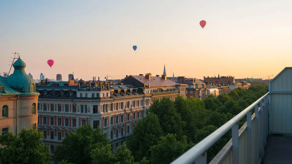 Luftballonger svävar över en europeisk stad vid solnedgång.