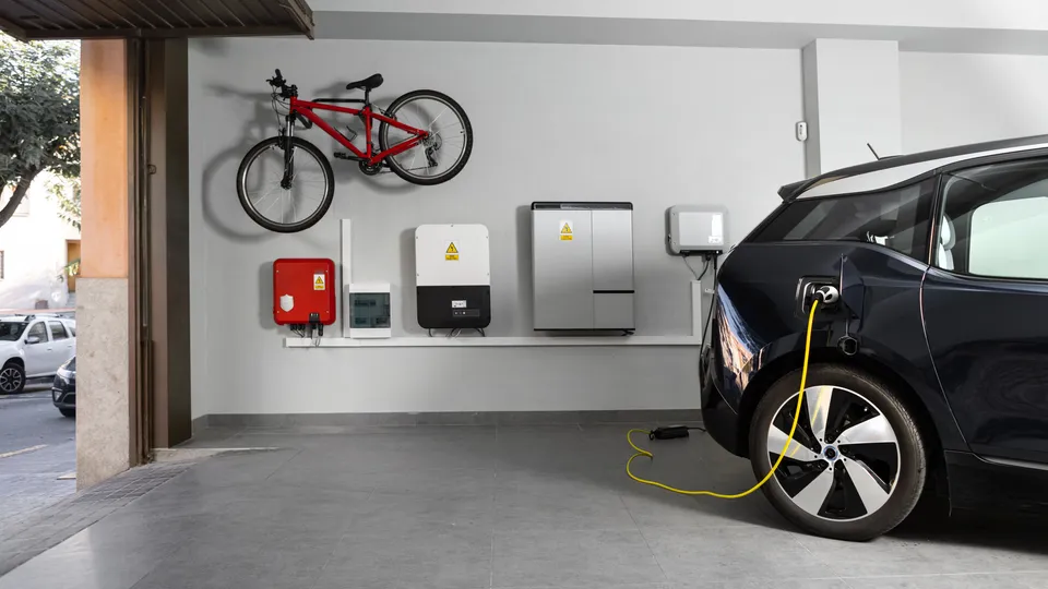 Svart elbil som lader i garasje med varmepumpe på veggen