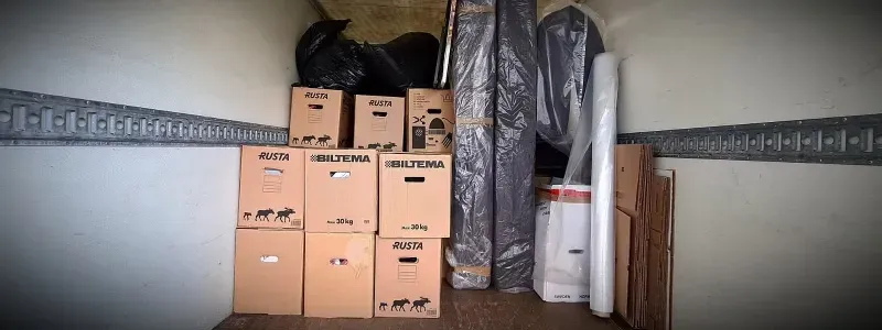 Kartonger och rullat material staplade på väggställningar.