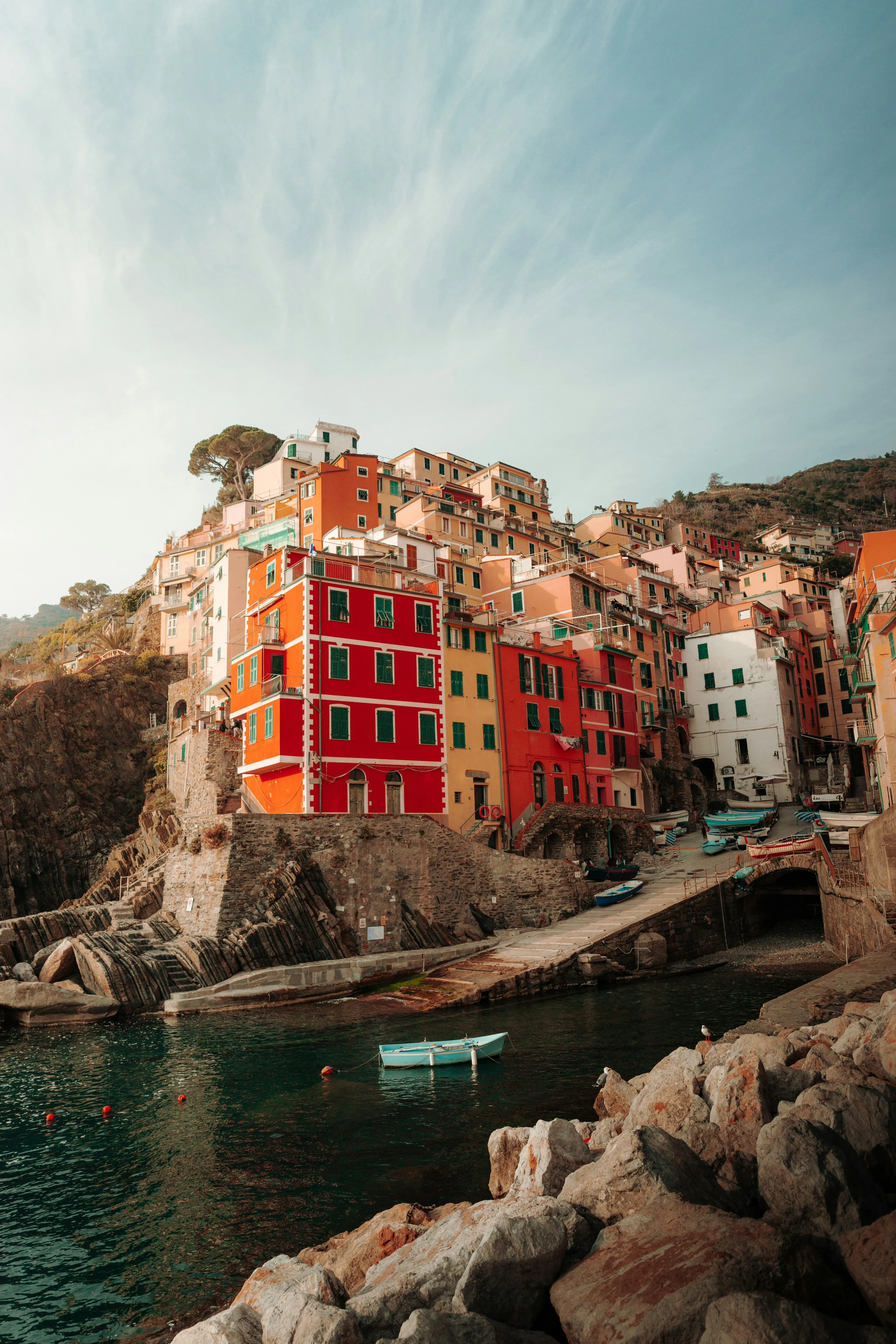 Edifici colorati arroccati su scogliere rocciose sopra un porto con barche.