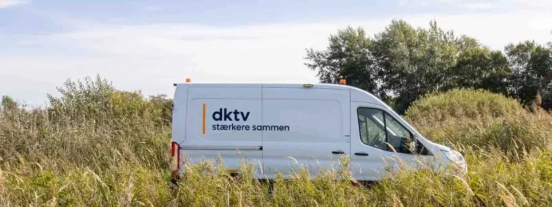 Varebil fra DKTV på en vej med natur.
