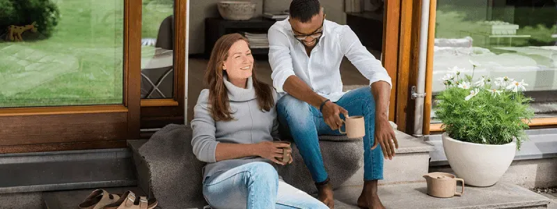 Bilde av en mann og en kvinne ved terrassen med en kopp kaffe hver