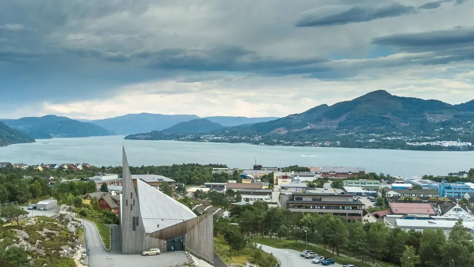 Knarvik sentrum med Knarvik kyrkje, fjord og fjell i bakgrunnen.