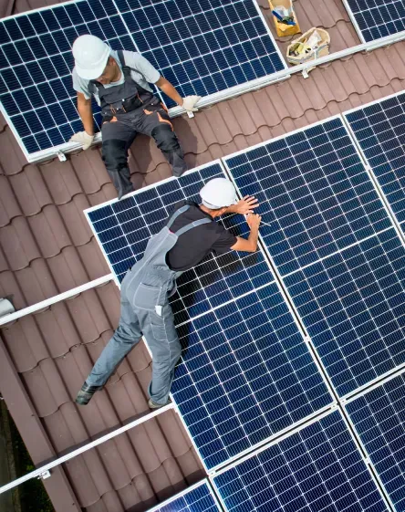 Dos trabajadores instalando paneles solares en un techo.