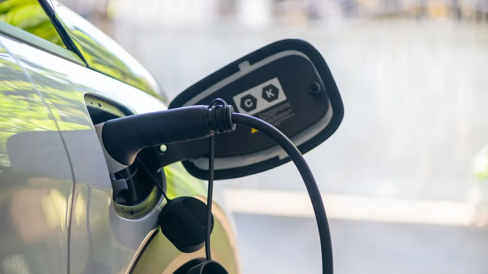 Close-up of a charging cable plugged into the charging port of an electric vehicle outdoors