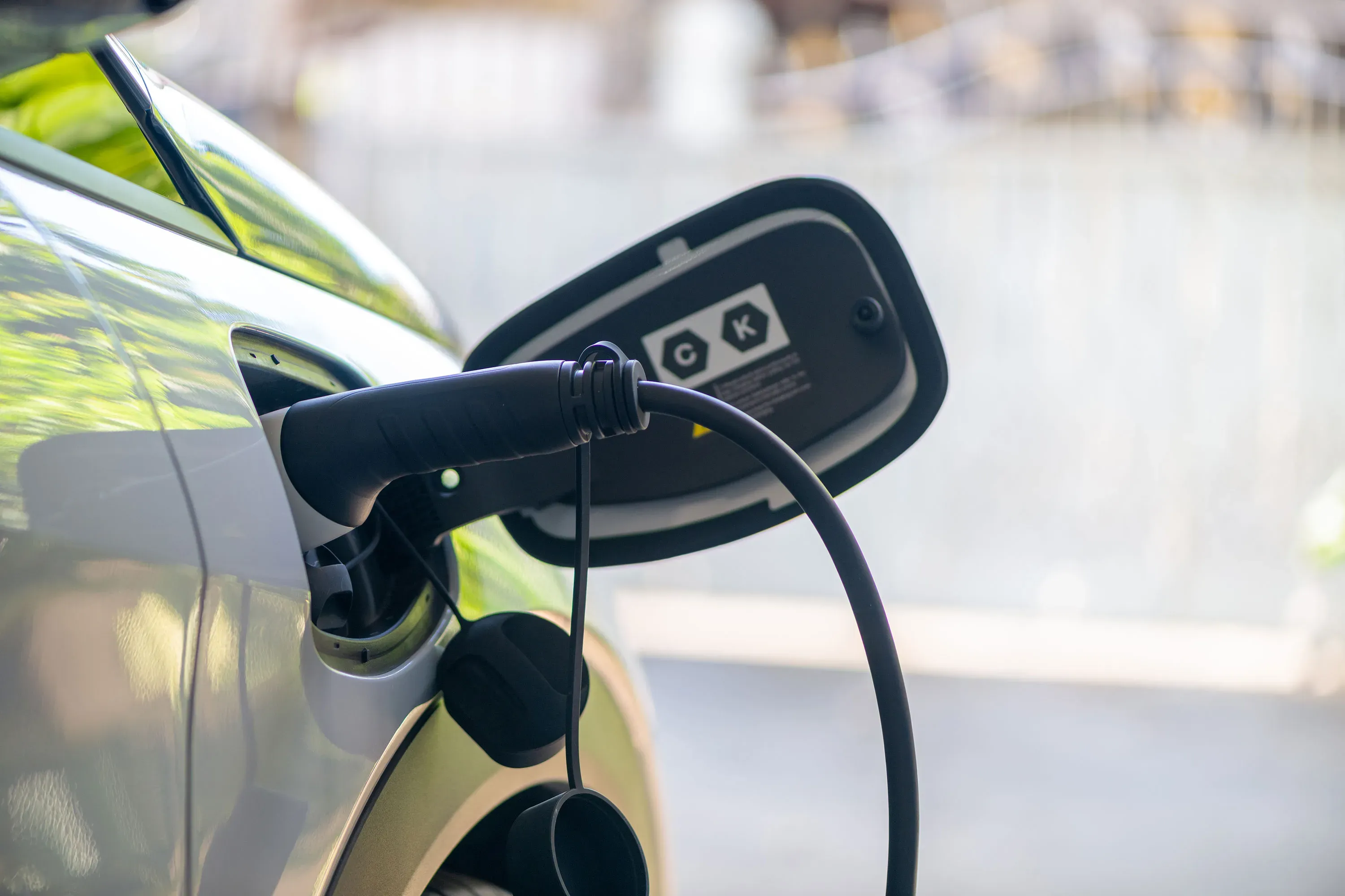 Close-up of a charging cable plugged into the charging port of an electric vehicle outdoors