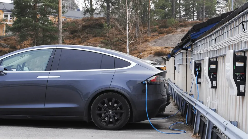 Elektrisk bil lades ved ladestasjonen med blå kabel.