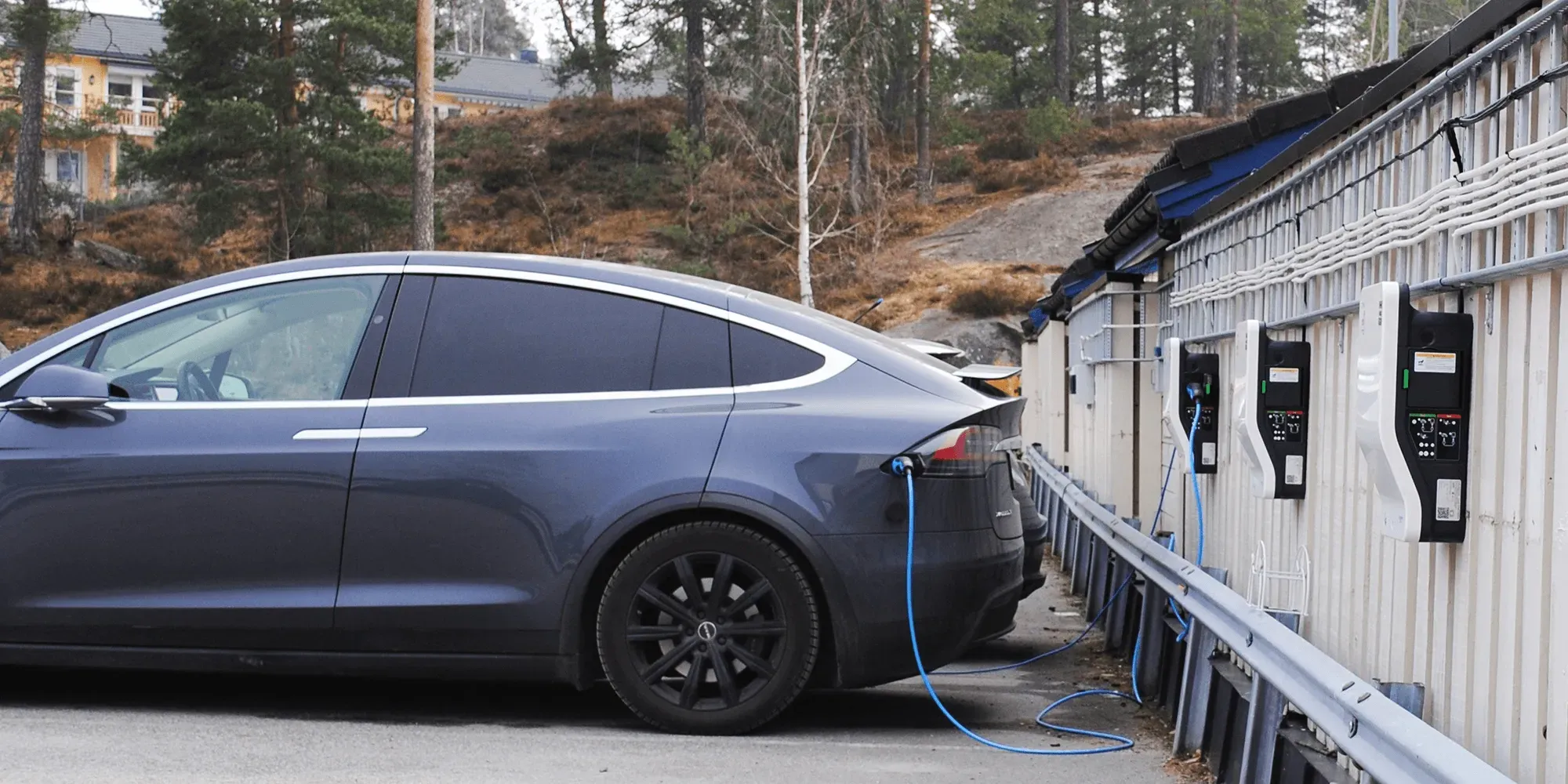 Elektrisk bil lades ved ladestasjonen med blå kabel.