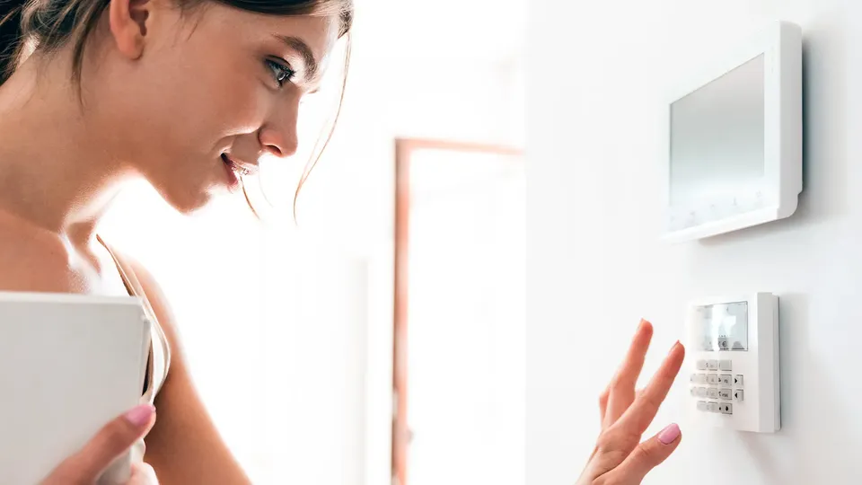 Mujer ajustando la alarma en la pared.