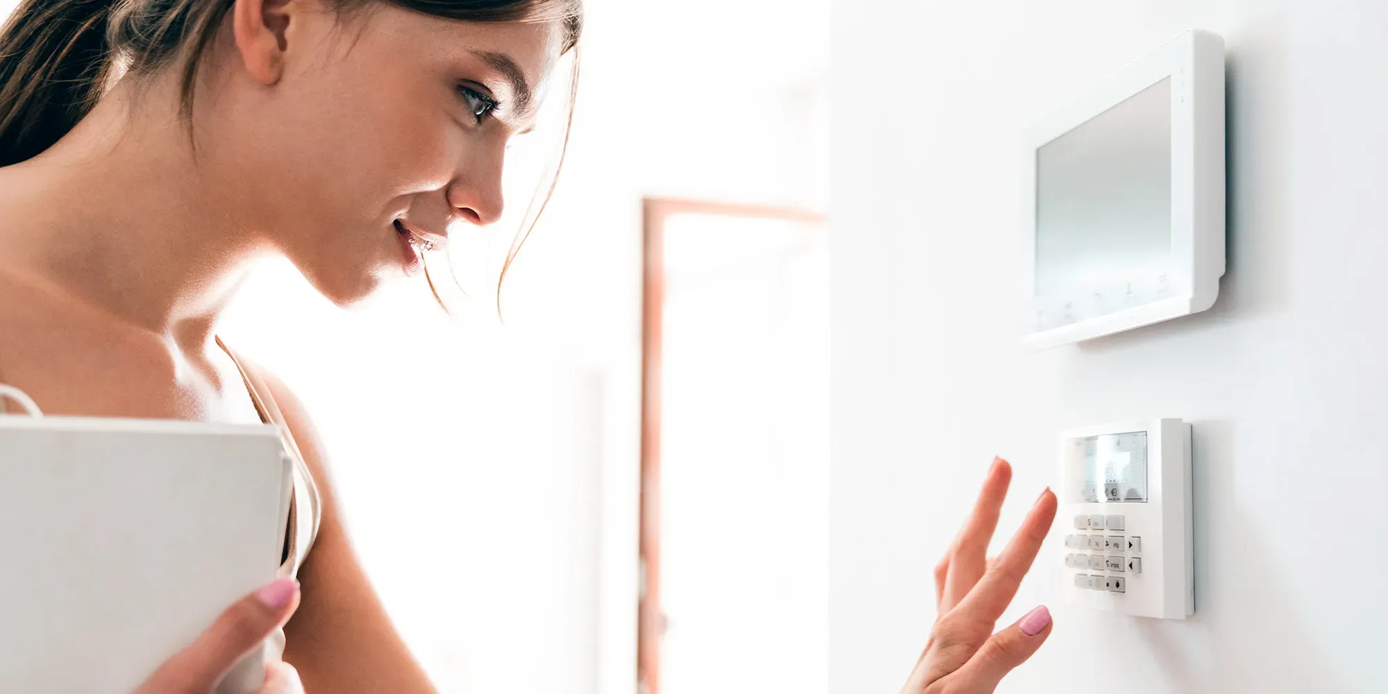 Mujer ajustando la alarma en la pared.