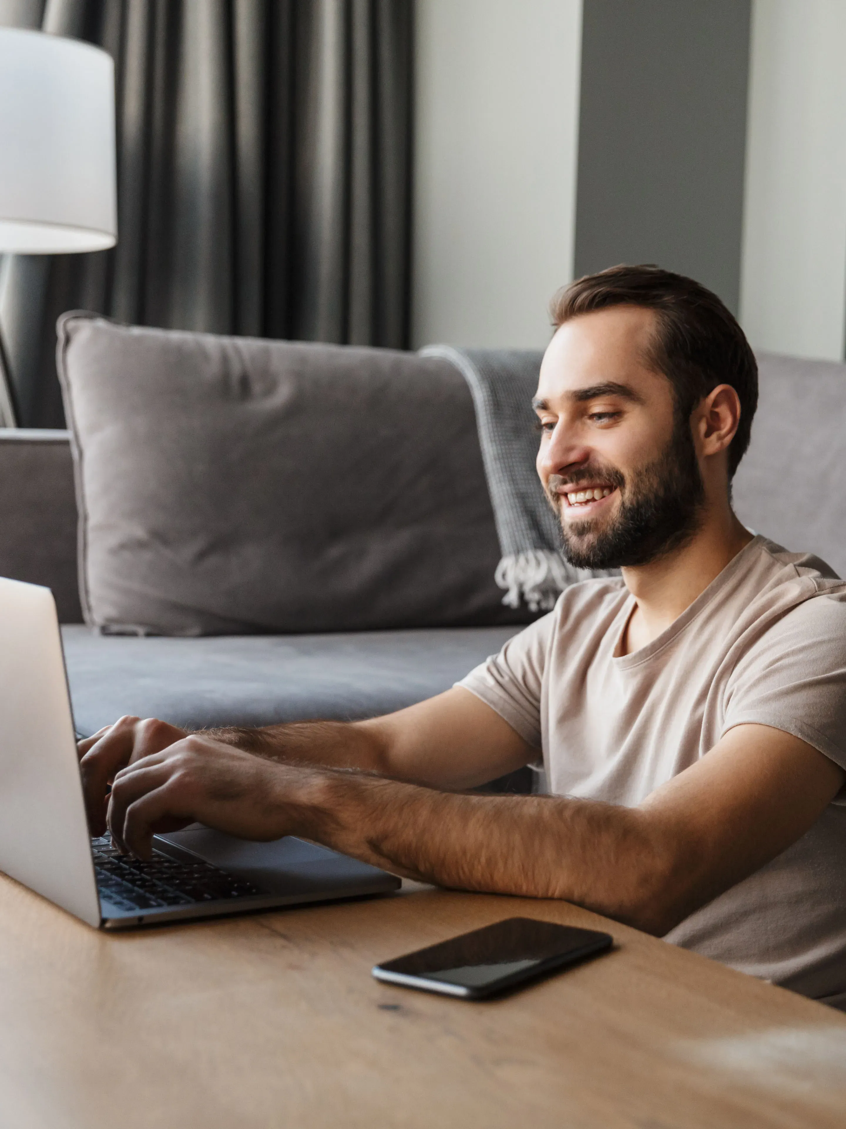 Hombre sonriendo mientras escribe en laptop en el escritorio.