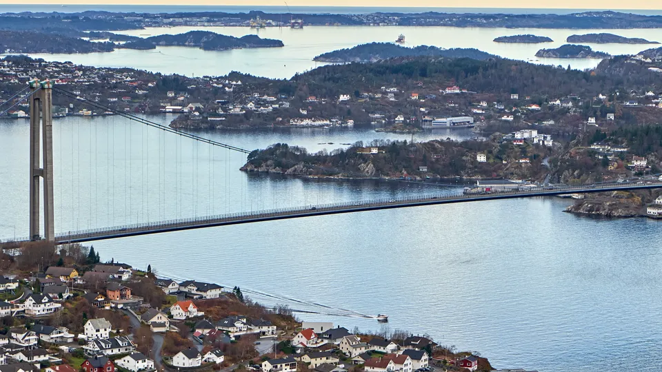 Hengebru som spenner over fjord med kysthusvær og øyer.