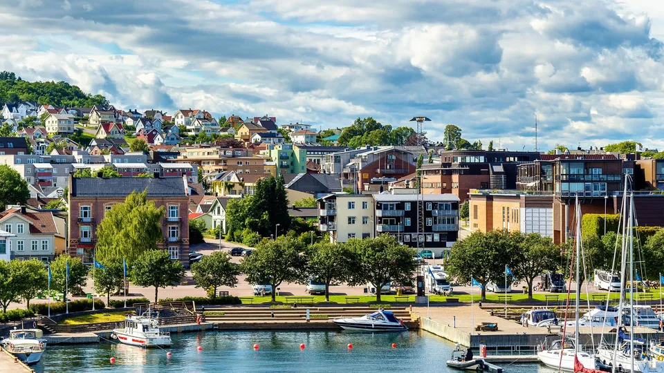 Kystby med fortøyde båter og hus på skråningen.