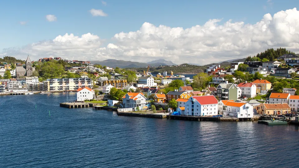 Kystby med fargerike bygninger langs fjorden.