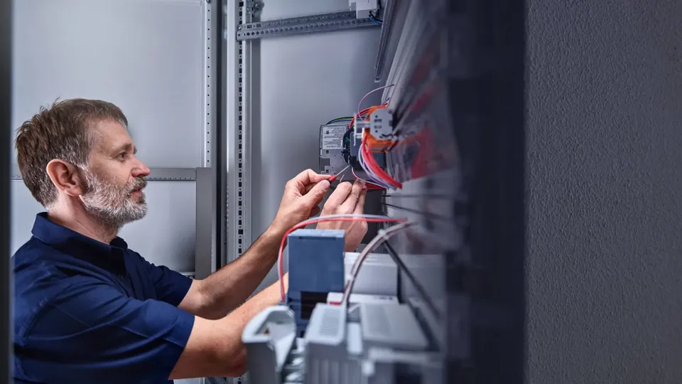 Elektriker arbejder på ledningsforbindelser i elskab.