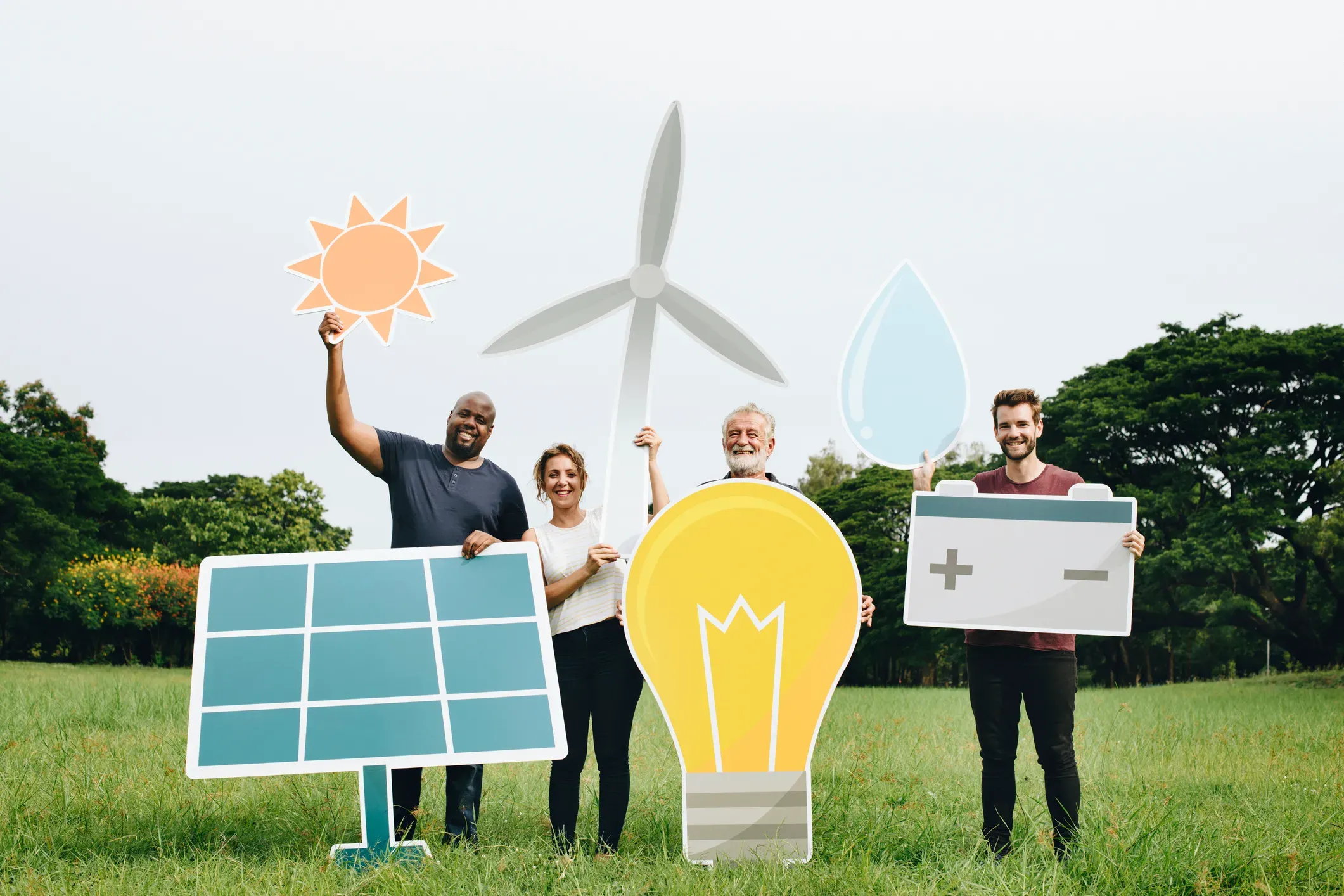 Gruppe von vier Personen hält Symbole für erneuerbare Energien wie Solarpanel, Windkraftanlage, Glühbirne und Wassertrop.