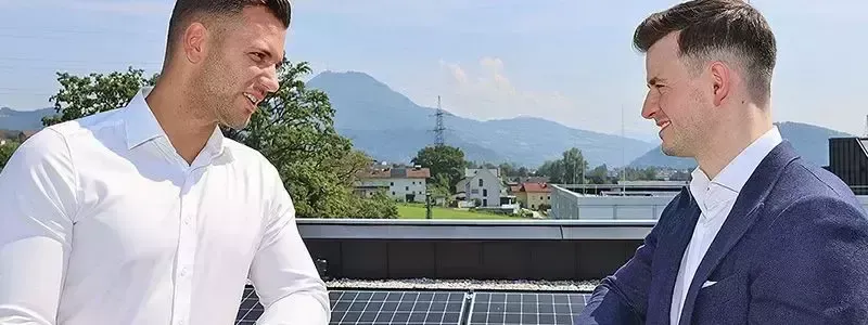 Zwei Männer unterhalten sich auf einem Dach mit Solarpanelen.