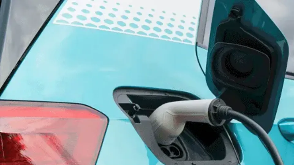 Electric vehicle charging cable plugged into turquoise car.