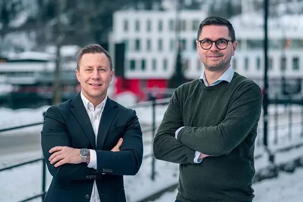Bilde av to meglere med handene i kors og ser i kameraet
