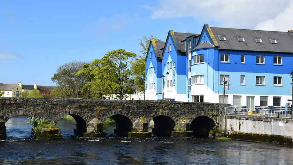 Blue and white building beside stone bridge spanning a river in County Sligo.
