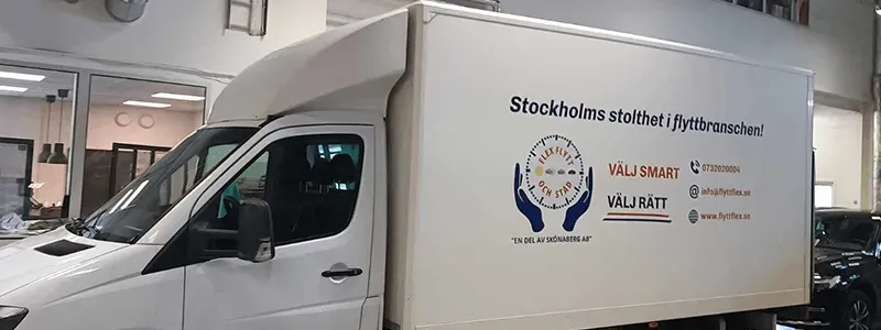 Bakgrundsbild för flyttfirman Flex Flytt, en flyttbil parkerad i en stor lokal.