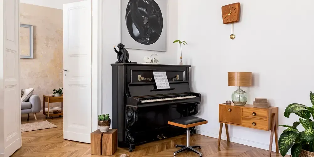 Svart pianino med träbänk i vardagsrum.