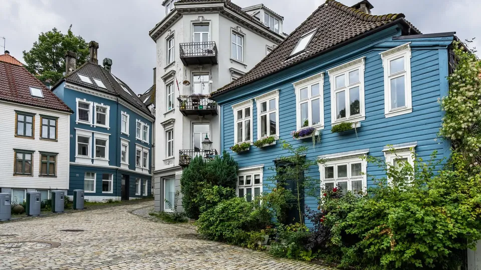 Eldre trehus langs en smal gate i Bergen, der adkomst kan påvirke flytting og valg av flyttebyrå