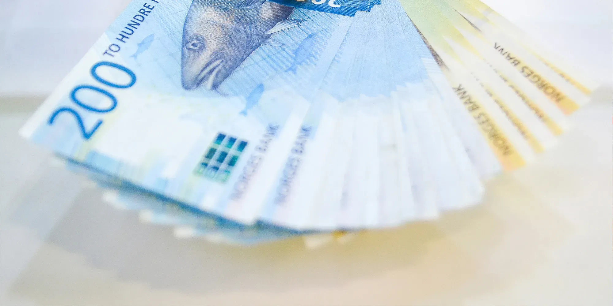 Stabel med kontanter spredt ut, viser 200 og 100 kronesedler.
