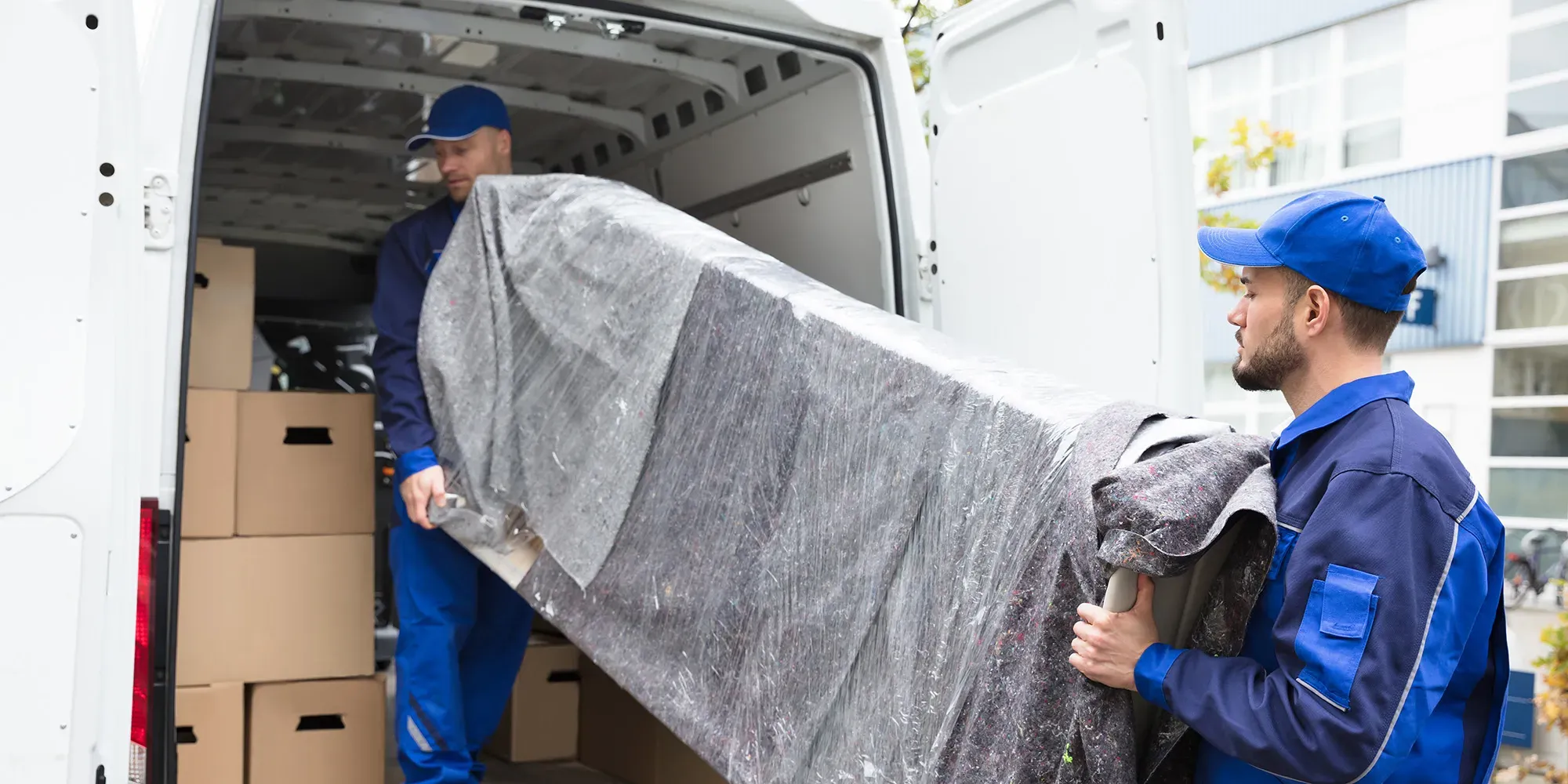To flyttearbeidere losser en pakket madrass fra en leveringsbil.