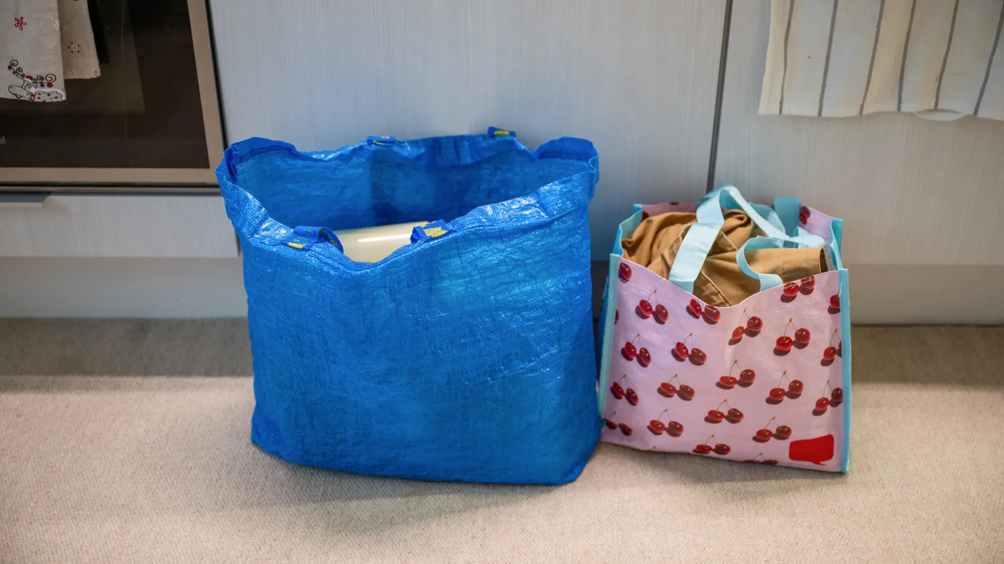 Två förvaringskassar i plast innehållandes kläder och hushållsartiklar.