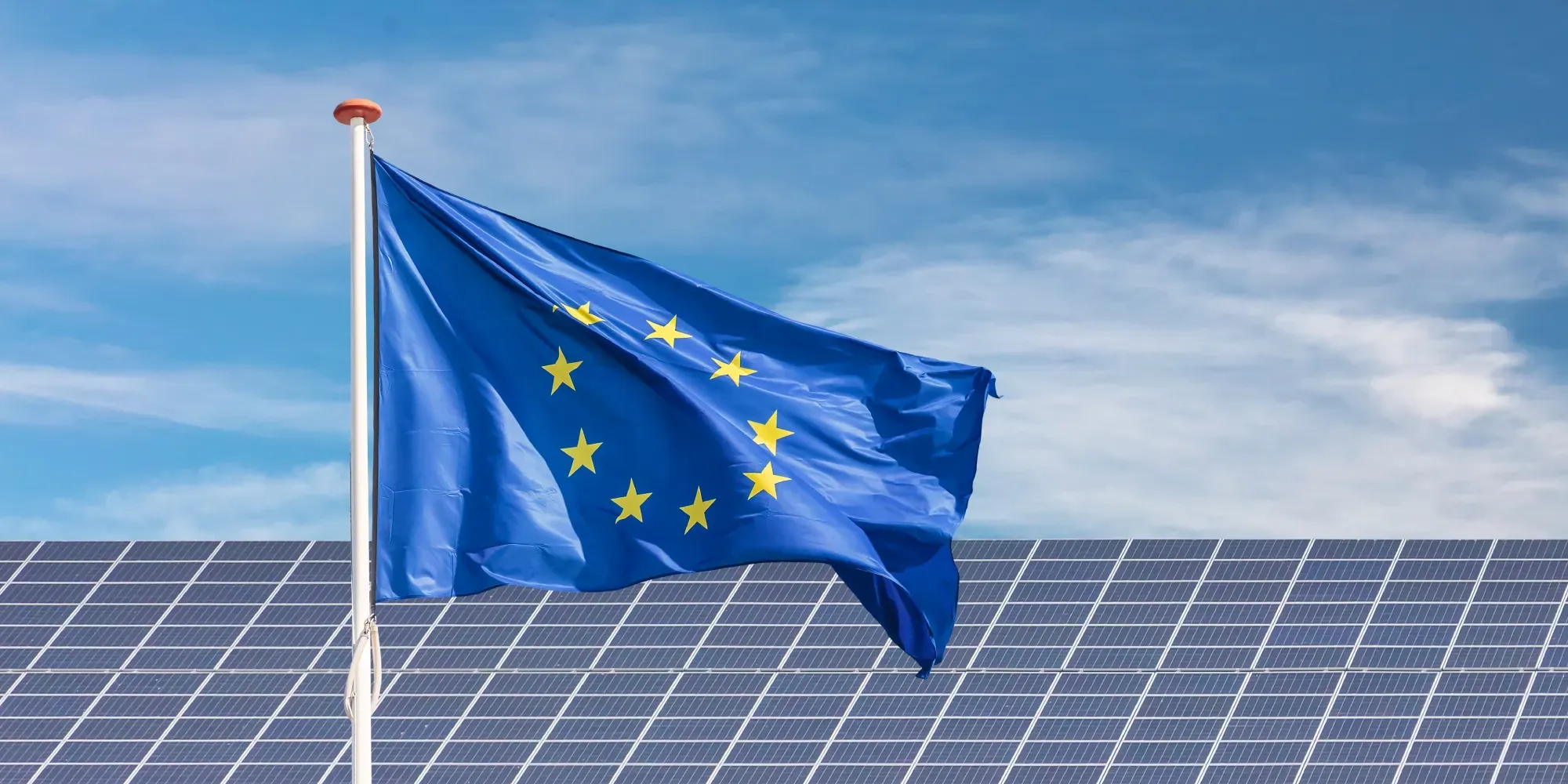 Bandera de la Unión Europea ondeando sobre paneles solares.